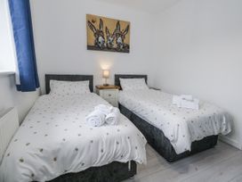 A bedroom with two beds and a painting at 8 Park View Grove in Weymouth