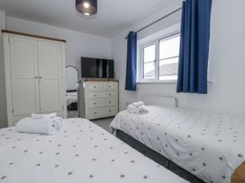 A bedroom with two beds and a television at 8 Park View Grove in Weymouth