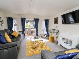 A living room with a sofa and television at 33 Woodpecker Lodge in Llanarth