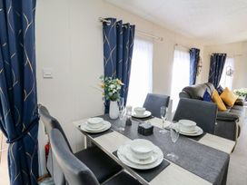 A dining area with a table set for meals at 33 Woodpecker Lodge in Llanarth