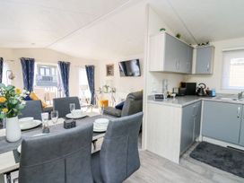 An open plan dining and kitchen area with table and chairs at 33 Woodpecker Lodge in Llanarth