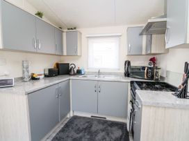 A kitchen with cabinets, sink, stove, and small appliances at 33 Woodpecker Lodge in Llanarth