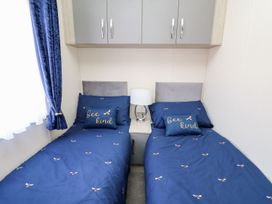A bedroom with two beds and a bedside table at 33 Woodpecker Lodge Llanarth