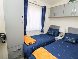 A bedroom with two beds and a window at 33 Woodpecker Lodge in Llanarth