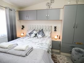A bedroom with a bed and nightstands at 33 Woodpecker Lodge in Llanarth