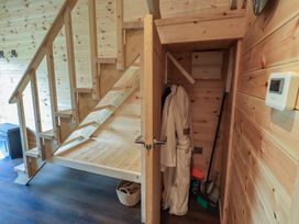 A staircase and storage area with a robe and basket at Bluebelle - Crossgate Luxury Glamping Hartsop