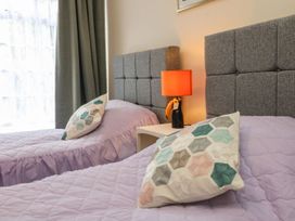 A bedroom with two beds and a lamp on a nightstand at Barton Lodge in Porlock