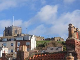 A castle is visible above rooftops in Whitby