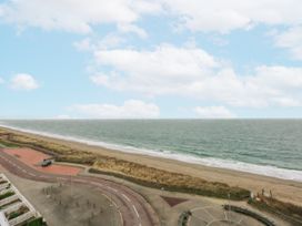 A view of the ocean and beach with a road and people at Snowdonia View in Pwllheli