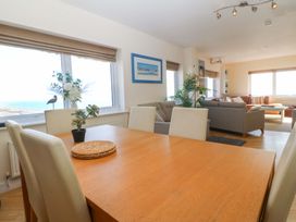 A dining room with a table and chairs overlooking the sea at Snowdonia View in Pwllheli