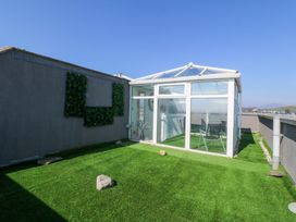 A conservatory with artificial grass and glass panels at Snowdonia View in Pwllheli