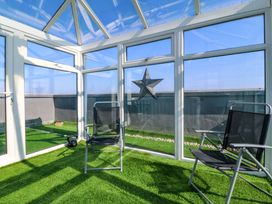 A conservatory with glass windows and chairs at Snowdonia View in Pwllheli