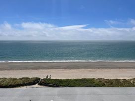 A view of the ocean and beach with people walking at Snowdonia View in Pwllheli