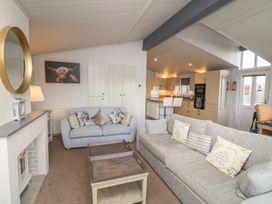 A living room with sofas and a kitchen area at Fairways 22 in Lincoln