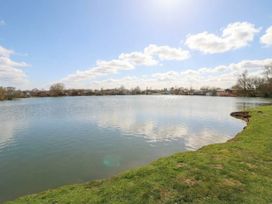 A lake with grass and trees at Fairways 22 Tattershall