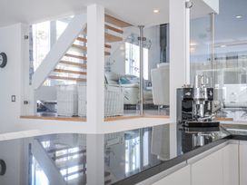 A kitchen with a coffee machine and staircase at The Cowshed in Portscatho