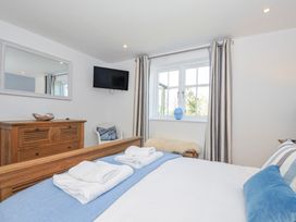 A bedroom with a bed and dresser at The Cowshed in Portscatho