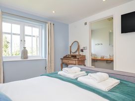 A bedroom with a bed and dresser at The Cowshed in Portscatho