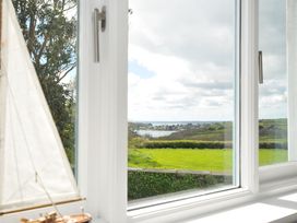 A view from a window showing a sailboat model and landscape at The Cowshed in Portscatho