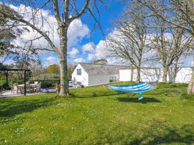 A garden with a hammock and dining area at The Cowshed in Portscatho
