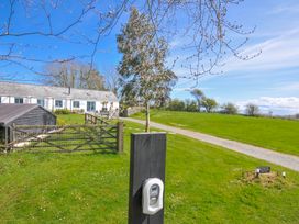 An outdoor view of a farmhouse with a gate and gravel path at The Cowshed in Portscatho