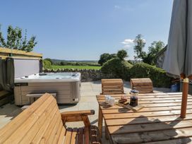 An outdoor area with a hot tub and wooden furniture at Ty Mawr Farm in Llanfairpwllgwyngyll