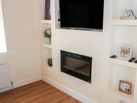 A living room with a television and electric fireplace at Greenfield House in Aughavas
