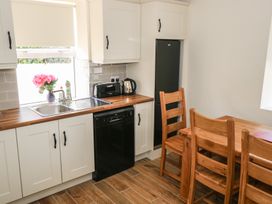 A kitchen with sink, dishwasher, refrigerator, and wooden table at Greenfield House in Aughavas