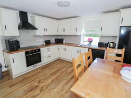 A kitchen with cabinets, an oven, and a dining table at Greenfield House, Aughavas, County Leitrim