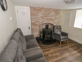 A living room with a sofa, an armchair, and a fireplace at Greenfield House, Aughavas, County Leitrim