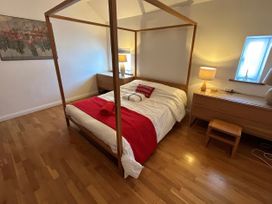 A bedroom with a four-poster bed and wooden furniture at Too Hoots in Lligwy
