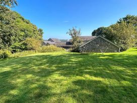 A garden with grass and trees at Too Hoots in Lligwy