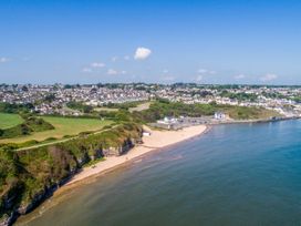 A beach along a coastline with houses and hills at Too Hoots in Lligwy