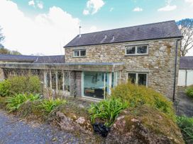 A stone house with windows and plants in front at Too Hoots Lligwy