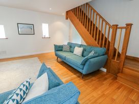 A living room with sofas and a staircase at Too Hoots in Lligwy