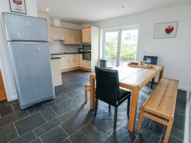 A kitchen with refrigerator and dining table at Too Hoots in Lligwy