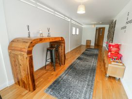 A hallway with a wooden table and storage unit at Too Hoots in Lligwy