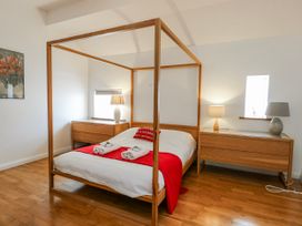 A bedroom with a four-poster bed and nightstands at Too Hoots in Lligwy