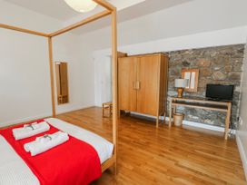 A bedroom with a bed and wardrobe at Too Hoots in Lligwy