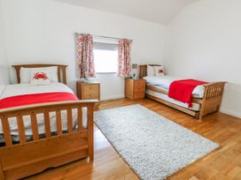 A bedroom with two beds and a nightstand at Too Hoots in Lligwy