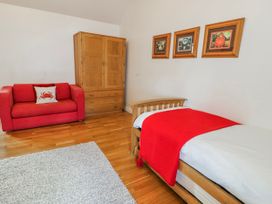 A bedroom with a bed and sofa at Too Hoots in Lligwy