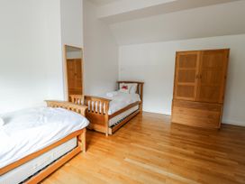 A bedroom with two beds and a wardrobe at Too Hoots in Lligwy