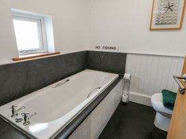 A bathroom with a bath tub and toilet at Too Hoots in Lligwy