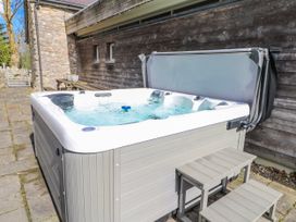 A hot tub beside a stone wall at Too Hoots in Lligwy