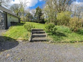 A garden with steps leading to grass and bushes at Too Hoots in Lligwy