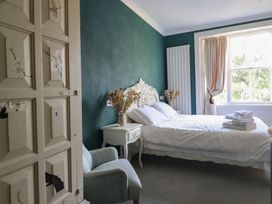 A bedroom with a bed and armchair at Plas Dolguog in Machynlleth