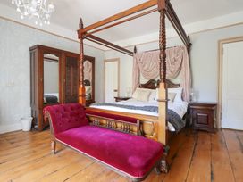A bedroom with a four-poster bed and a wardrobe at Plas Dolguog in Machynlleth