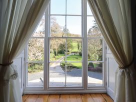 A view of a garden and driveway through a window at Plas Dolguog in Machynlleth