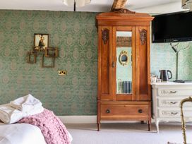 A bedroom with a wooden wardrobe and a television at Plas Dolguog in Machynlleth