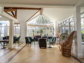 A conservatory with seating and plants at Plas Dolguog in Machynlleth